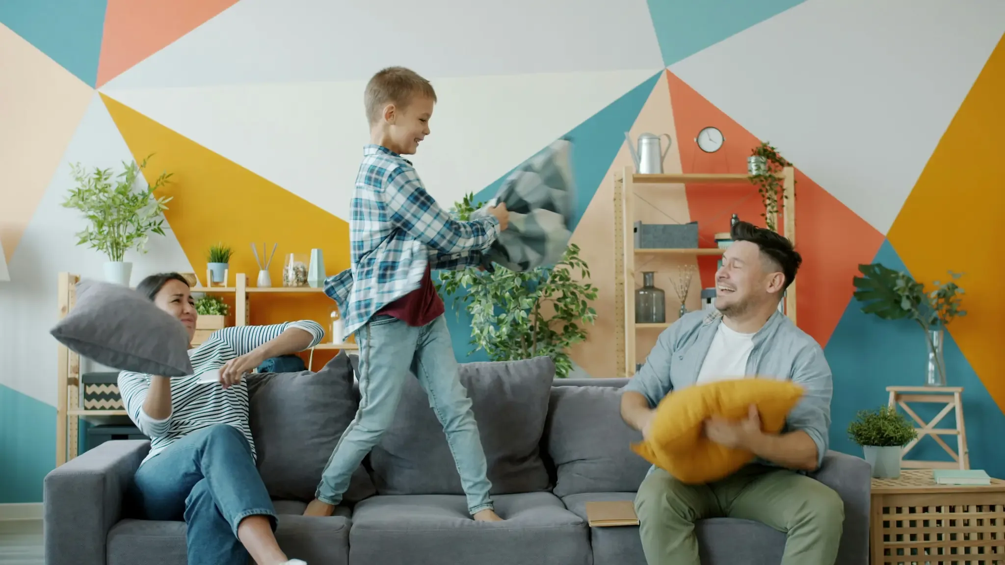 Familie macht eine Kissenschlacht im bunten Wohnzimmer