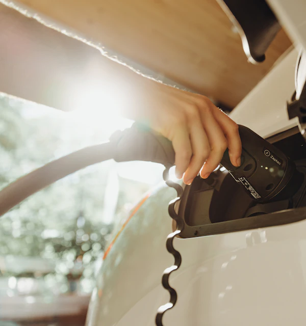 Hand steckt das Ladekabel in ein Elektroauto