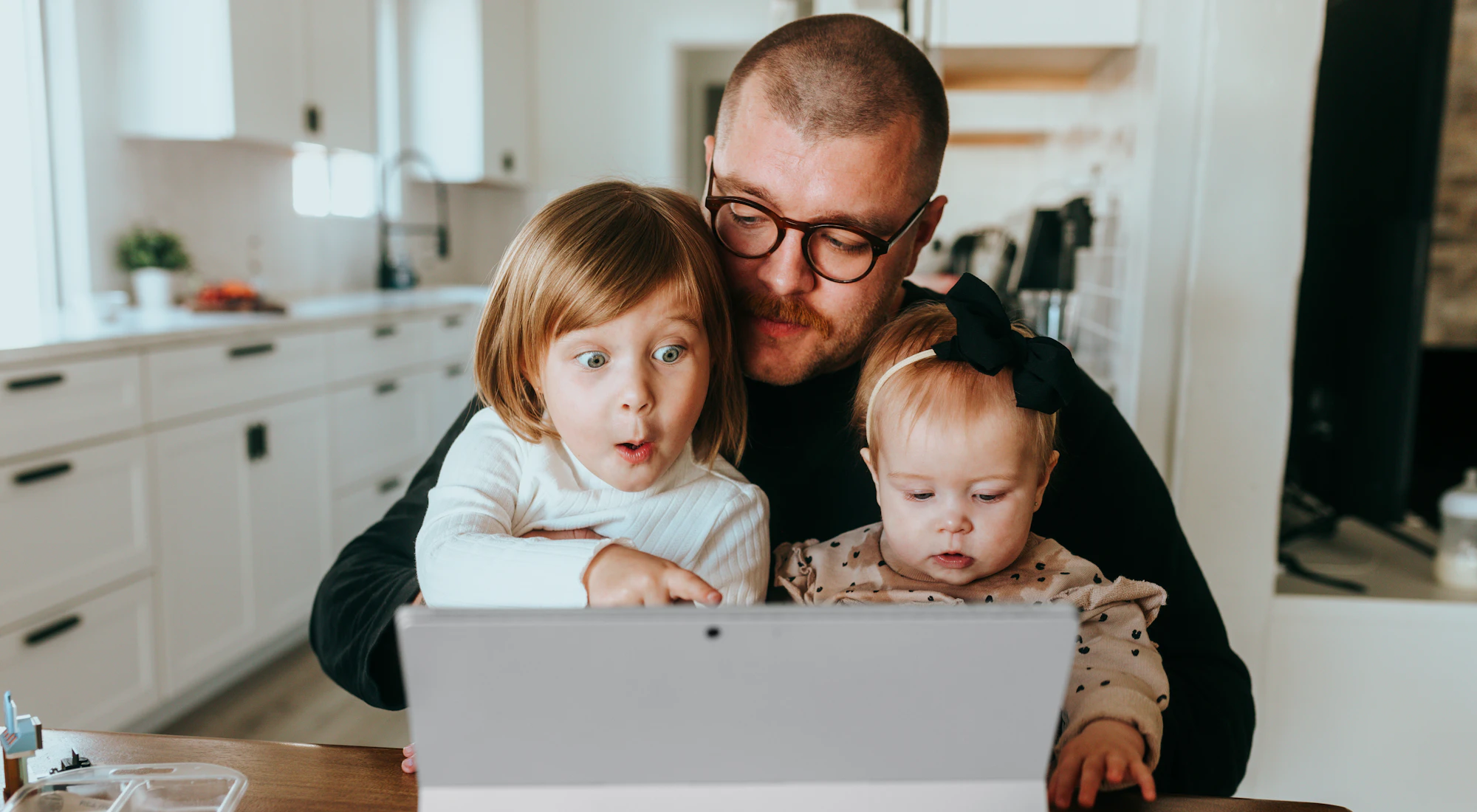 Vater und zwei Kinder schauen gemeinsam auf den Laptop