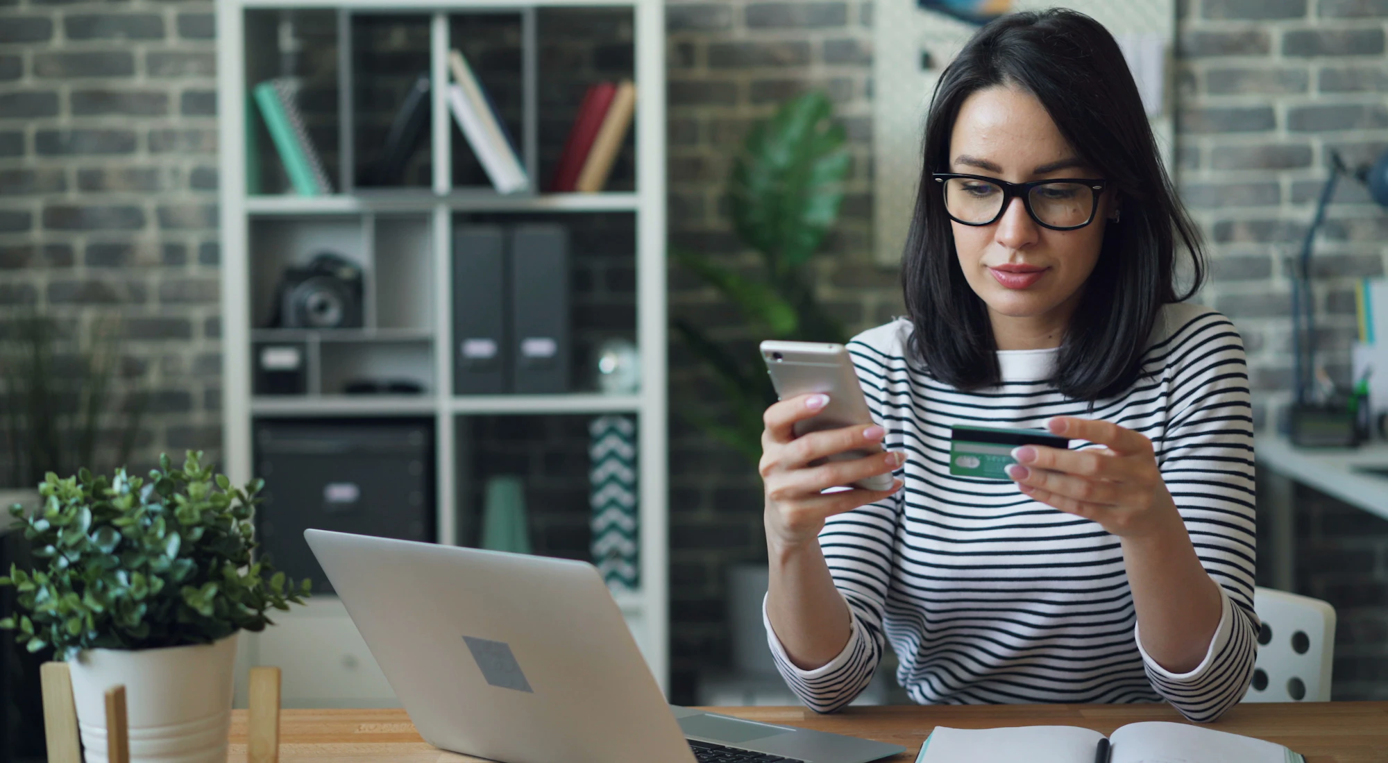 Frau am Tisch schaut entspannt auf ihr Smartphone
