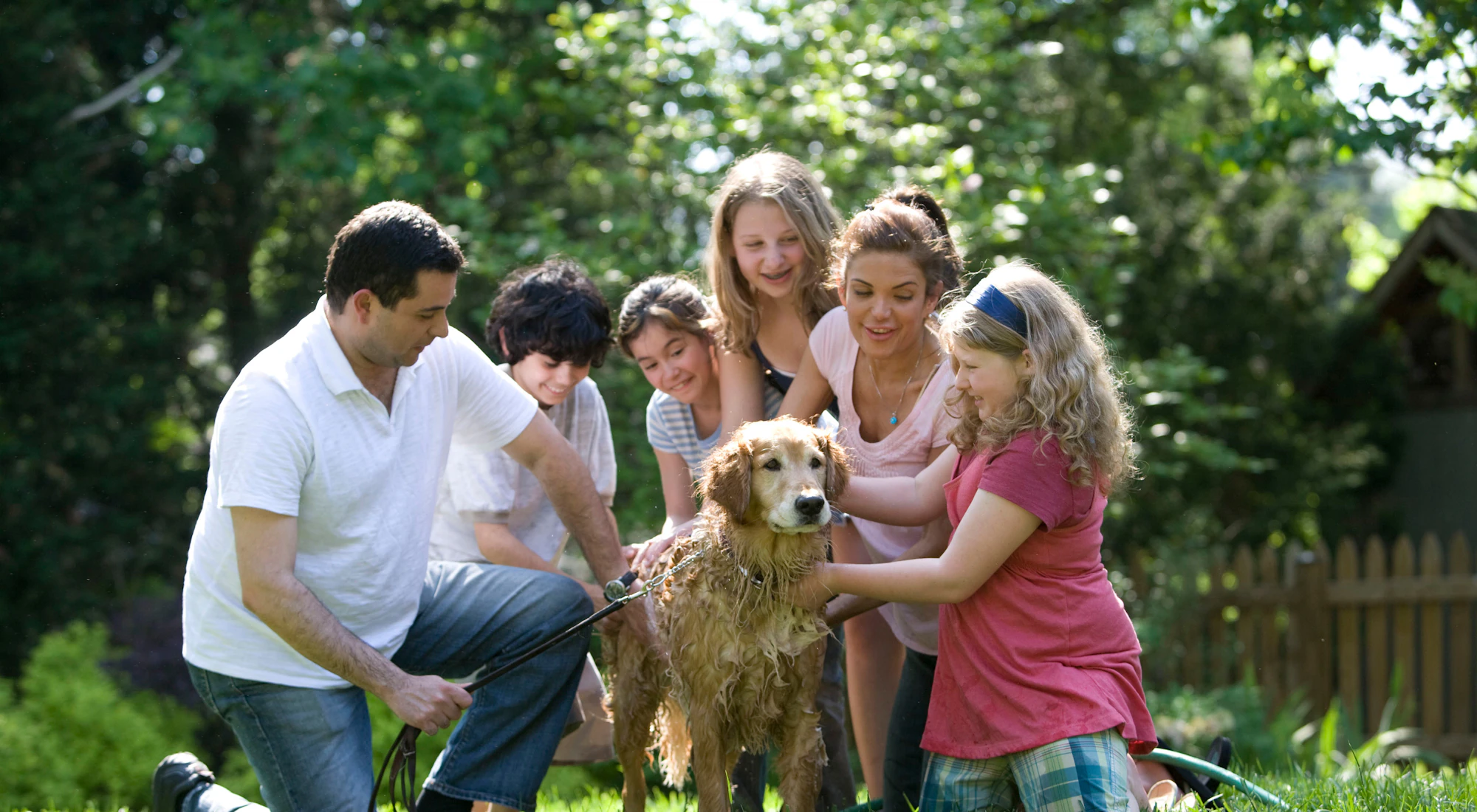 Familie wäscht ihren Golden Retriever im Garten